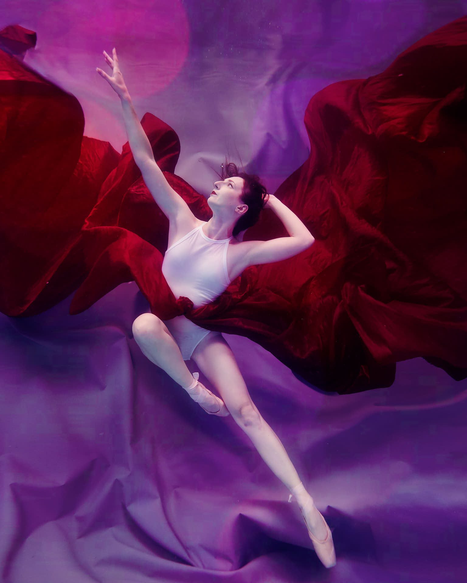 Underwater ballet photoshoot, purple backdrop, red fabric, white leotard, ballet, ballet shoes, en pointe
